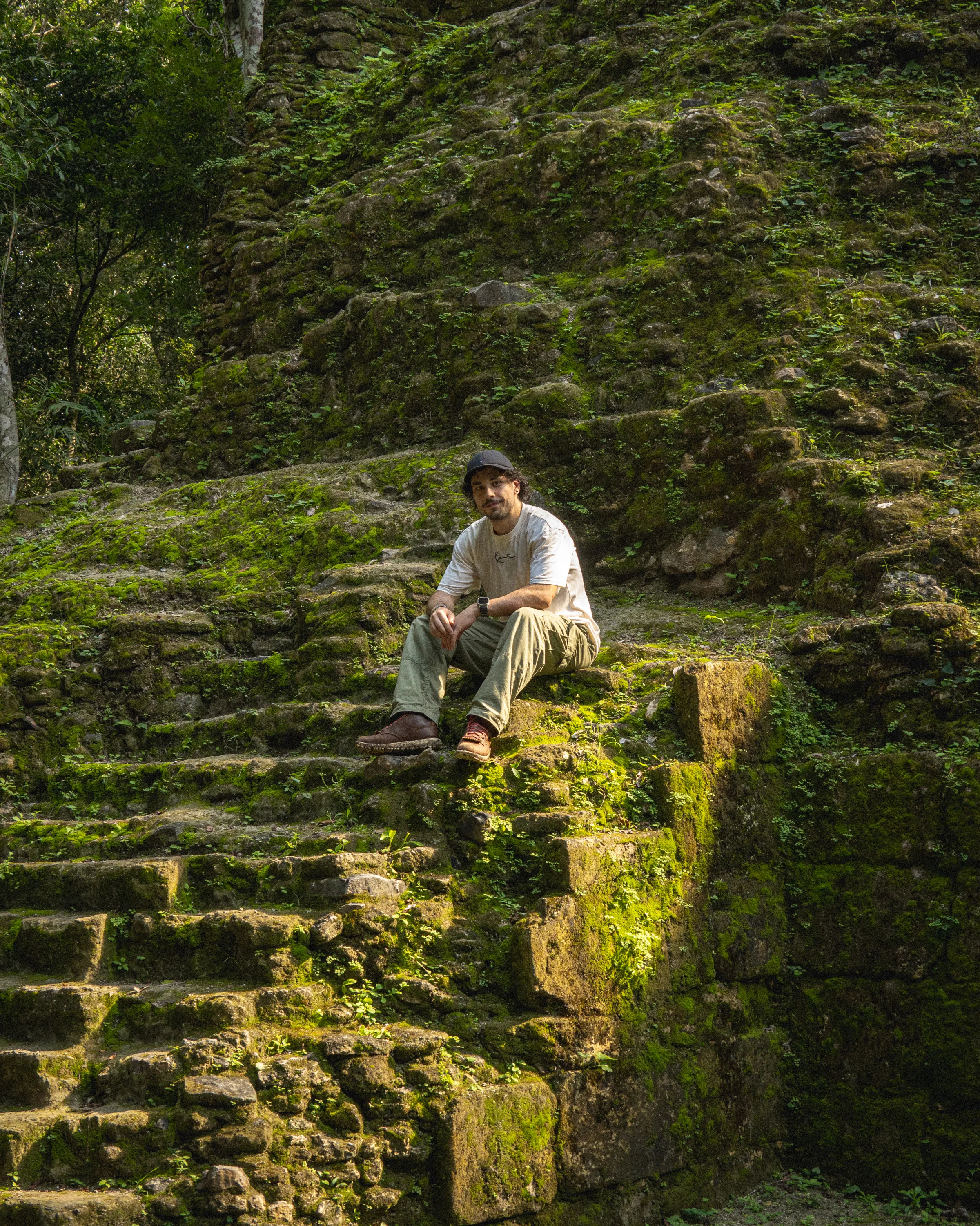 Javi sitting on moss-covered ruins at El Mirador in Guatemala