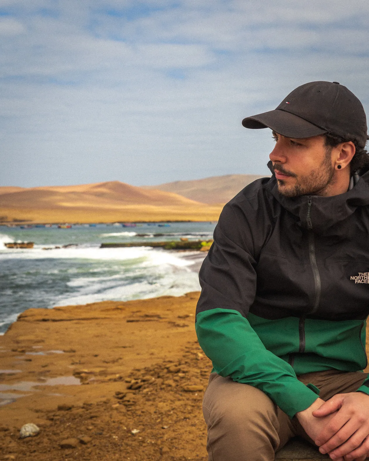 Javi sitting beside a rocky coastline